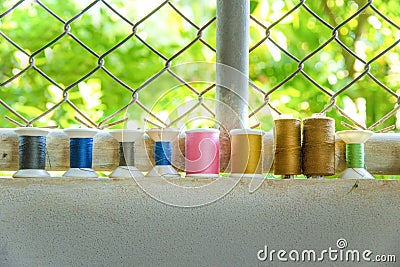 Colourful used thread spools on wall with green background Stock Photo