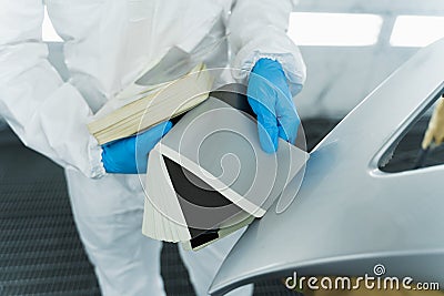 Colourist man selecting color of car bumper with paint matching samples. Stock Photo