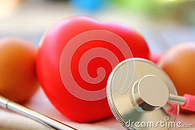 Close up stethoscope check up red heart with eggs on white cloth .medically eating egg everyday helps to reduce heart problem Stock Photo
