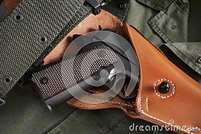 Colt pistol in holster and belt lie on military jacket Stock Photo