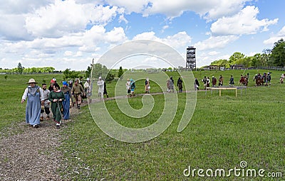 A column of people dressed in medieval clothes are walking along a winding path in the park Editorial Stock Photo