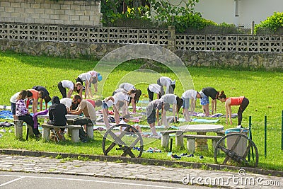 COLUNGA, SPAIN - Jun 01, 2016: yoga teacher and children learning yoga on the grass Editorial Stock Photo