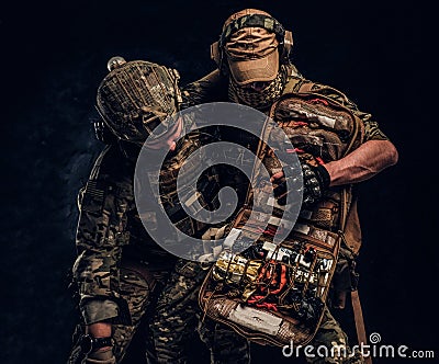 Combat conflict, special mission, retreat. Military medic rescues his wounded teammate carrying him off the battlefield. Stock Photo