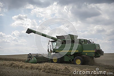 The combine harvests the ripe golden wheat in the grain field. Agricultural work in summer. Ãšri, Hungary - 22/07/2020 Editorial Stock Photo