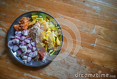 Combined indian spices and ingredients for making curry in a steel plate with wooden background Stock Photo