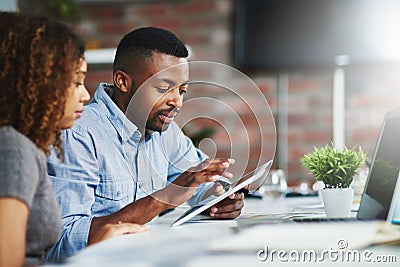 Combining their contributions into one. two colleagues using a digital tablet in an office. Stock Photo