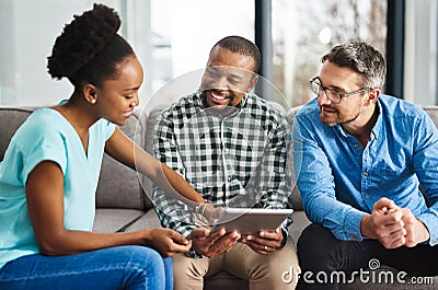 Combining their ideas to make it better. a creative team discussing something on a digital tablet. Stock Photo