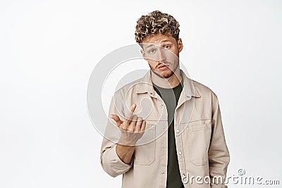 Come closer. Sassy blond handsome guy luring, twitching finger, beckon to approach him, standing over white background Stock Photo
