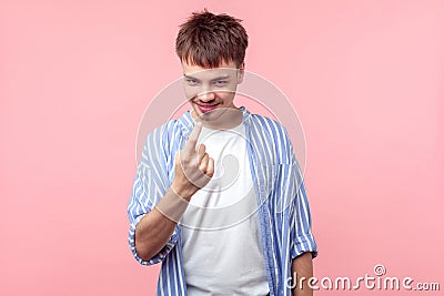 Come here! Portrait of cunning brown-haired man making beckoning gesture. isolated on pink background Stock Photo