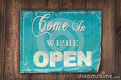 Come in we're open sign on an old wooden background Stock Photo