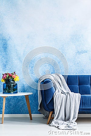 Comfortable dark blue settee with gray blanket and small side ta Stock Photo