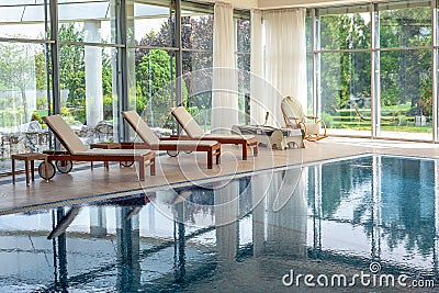 Comfortable indoor swimming pool in country house with chaise lounges, massage bed and rocking chair Stock Photo