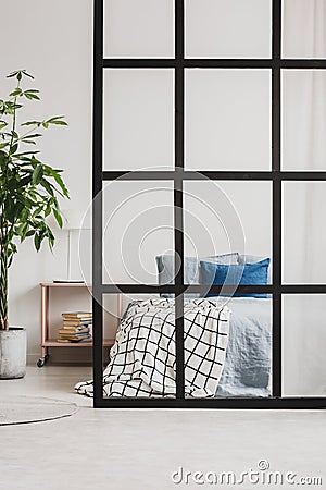 Comfortable king size bed with blue bedding in bright open plan studio apartment with partition Stock Photo