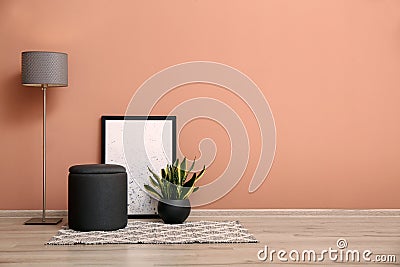 Comfortable pouf, plant, lamp and picture near pale pink wall indoors, space for text Stock Photo