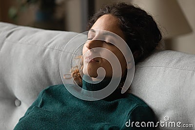 Calm millennial latina woman taking break for relax on couch Stock Photo