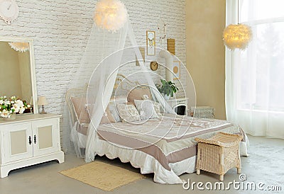 Comfortable simple bedroom with light-colored furniture, four-poster bed, feather lamps, small fireplace on wood, cosy modern Stock Photo