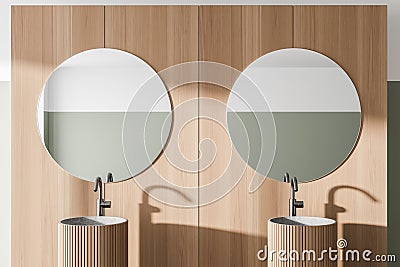 Comfortable two sinks with round mirrors standing on countertop in modern bathroom with wooden walls Stock Photo