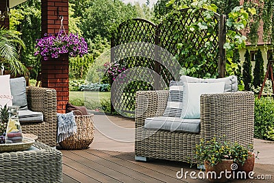 Comfy wicker armchair with pillows on wooden terrace of trendy suburban home Stock Photo