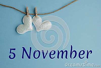 Commemorative date November 5 on a blue background with white hearts with clothespins, flat lay. Holiday calendar concept World Stock Photo