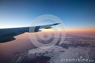 Commercial Aviation Jetplane flying over the ice mountain landscape on the Ocean Coast of Greenland. Stock Photo
