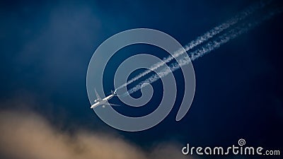 Commercial passenger aircraft flying over a blue sky, leaving a trail of contrails Stock Photo