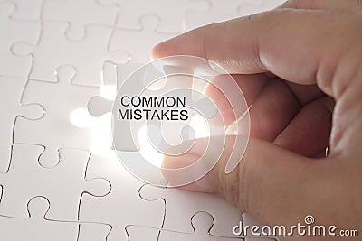 COMMON MISTAKES word on jigsaw puzzle. Businessman hands holding Stock Photo