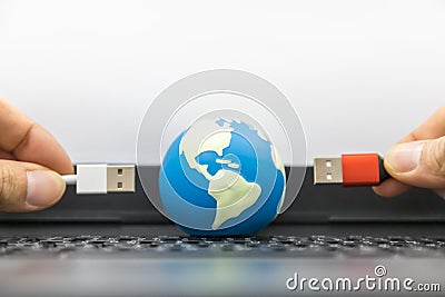 Communication, Computer and Global Technology Concept. Close up of mini world ball with mand hand holding USB cable on computer Stock Photo