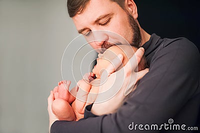 Communication father and son. Holiday concept Father`s Day. Father with a beard holds a newborn in his arms on a black background Stock Photo