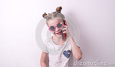 Communication technologies: A girl in pink glasses emotionally talks on the red phone. Stock Photo