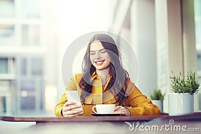 Happy woman texting on smartphone at city cafe Stock Photo