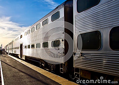 Commuter train diminishes into sunset after dropping off passengers. Stock Photo