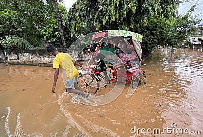Commuters on a rickshaw to cross a waterlogged road after heavy rainfall, on October 6, 2023 in Guwahati, Assam, India. Severe wat Editorial Stock Photo