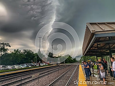 Commuters wait for the train while standing on a Chicago suburbs station platform during a stormy summer morning Editorial Stock Photo