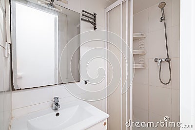 Compact white old tiled bathroom with shower and sink in need of renovation. Concept of preparing the premises for the Stock Photo