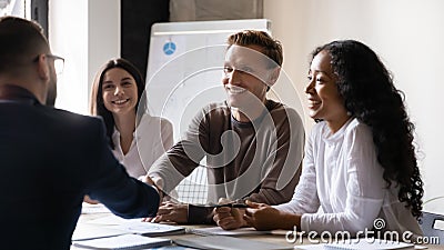 Company boss greeting client start negotiations shake hands express respect Stock Photo