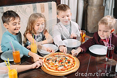 Company of children eat pizza in the restaurant Stock Photo