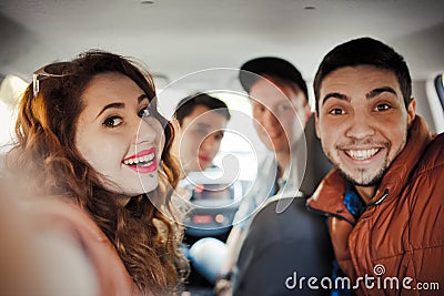 A company of four friends makes selfie inside the car Stock Photo