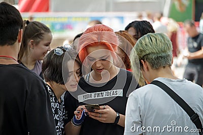 Company of modern informal youth at the festival, couple of girls use phone, youth mob in big city Editorial Stock Photo