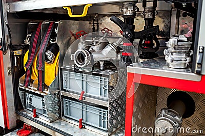 Compartment of rolled up fire hoses on a fire engine. Rescue fire truck equipment. A silver fire hydrant with red valves and other Stock Photo