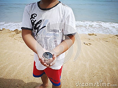 A boy holding a compass showing the direction point to north. Stock Photo