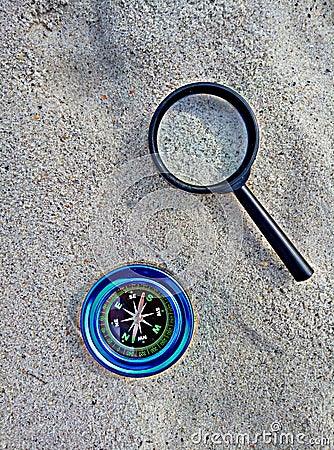 Compass and magnifier on sand Stock Photo