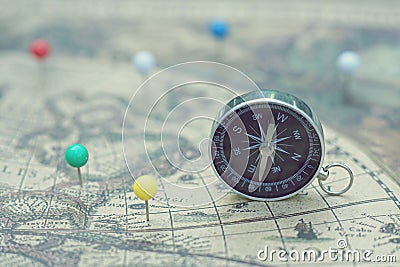 Compass and marking pins on blur vintage map, journey concept Stock Photo