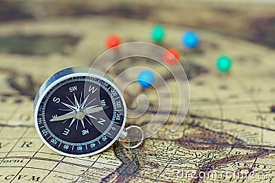 Compass and marking pins on blur vintage world map, journey concept Stock Photo