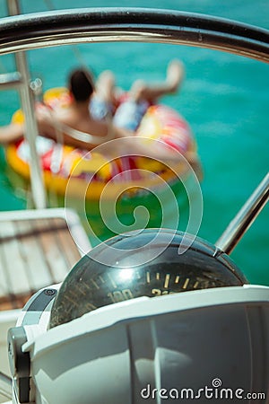 Compass on a yacht boat. In the background there is a man floati Stock Photo