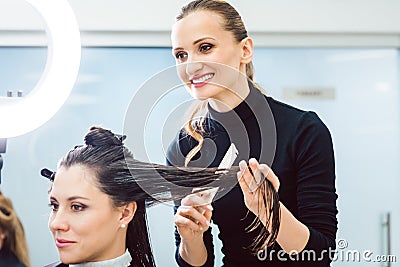 Hairdresser cutting and styling hair of woman in her shop Stock Photo