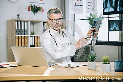 Competent mature therapist analysing results of x ray scan Stock Photo