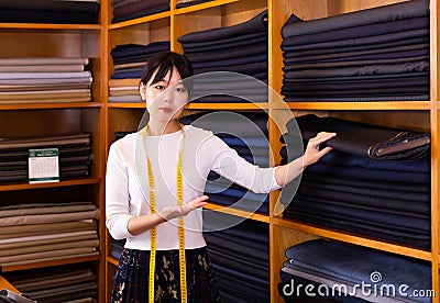 Competent young saleswoman offering various interesting cloth in textile shop Stock Photo