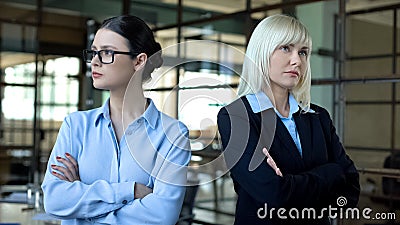 Competing women standing in office, colleagues in conflict, leadership challenge Stock Photo