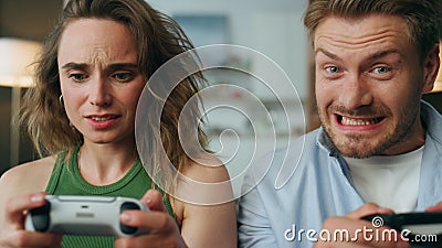 Competitive pair holding gamepads home portrait. Nervous woman losing pov video Stock Photo