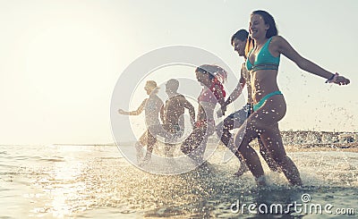 The complete family runs hand in hand from the beach to the sea, enjoying a joint vacation by the sea Stock Photo
